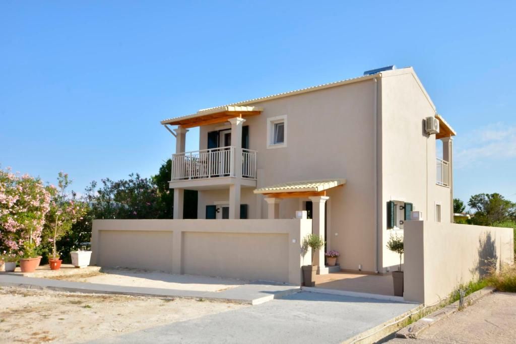 Exterior of the two-storey villa with its balcony, covered entrance and parking area